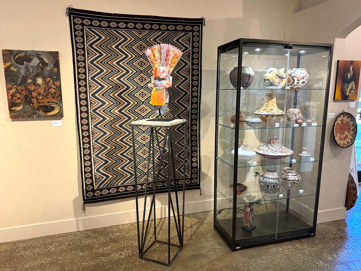 Sculpture on table next to ceramics display in glass cabinet