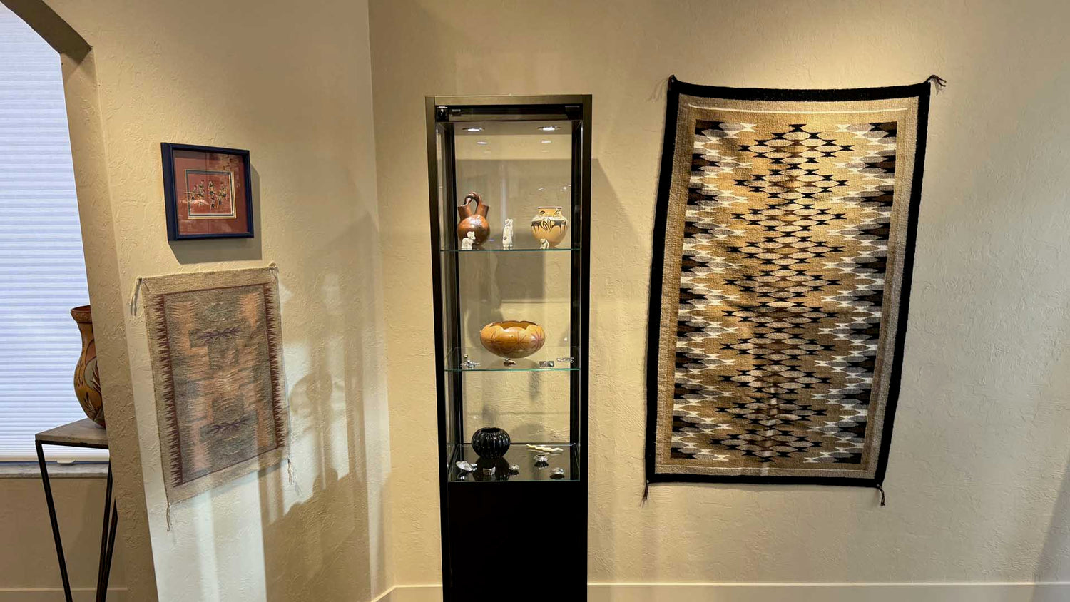 Room interior with a display cabinet, framed artwork, and decorative items on a wall.