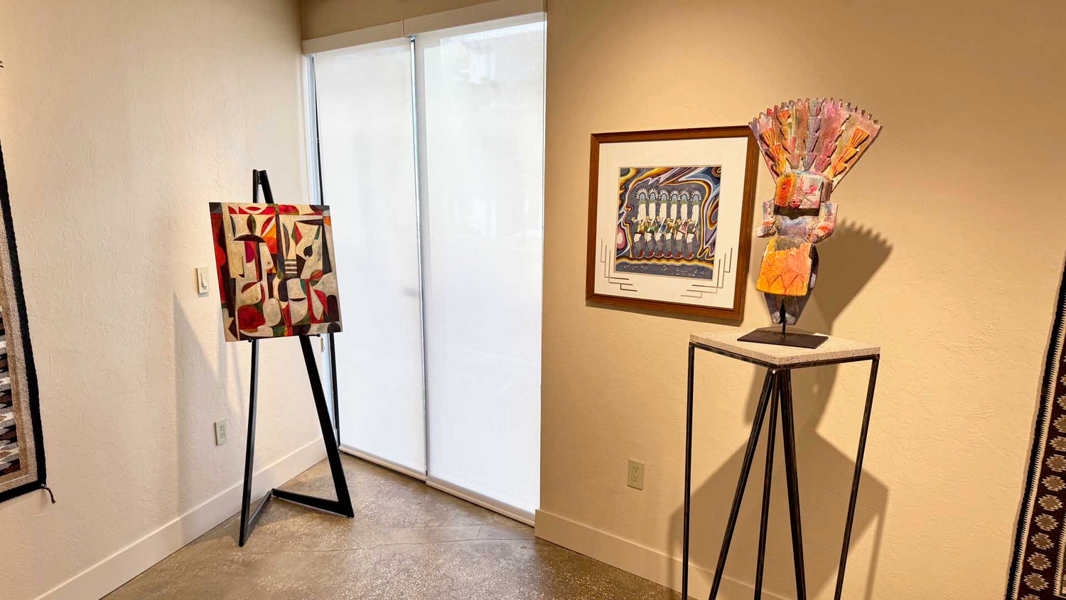 Artistic lampshades on stands with framed artwork on a wall in a room.