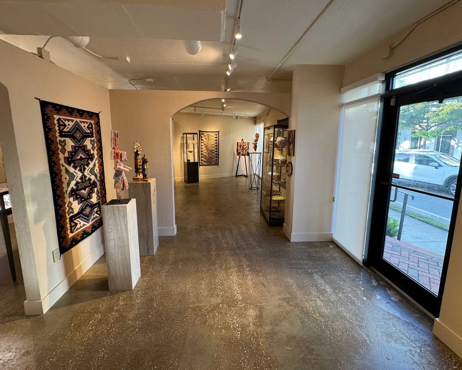 Art gallery with artworks on the walls and a view of the street outside.